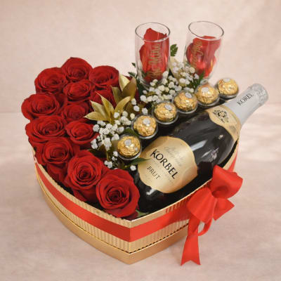 Heart-shaped gift box with red roses, chocolates, and two champagne flutes