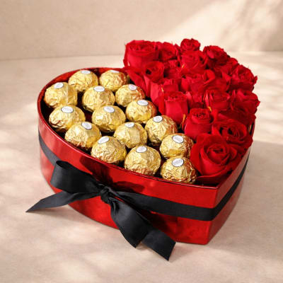 Heart-shaped box of red roses and gold-wrapped chocolates with a black ribbon