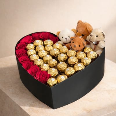 Heart-shaped gift box with red roses, gold chocolates, and small teddy bears