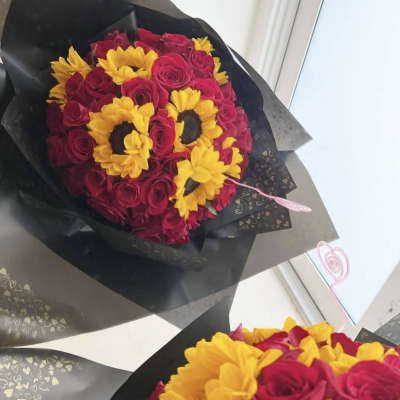 Bouquet of red roses with yellow sunflowers wrapped in black paper