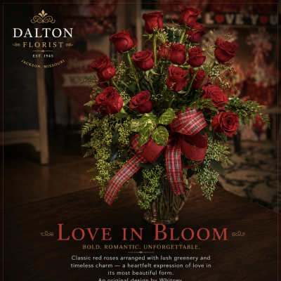 Red roses arranged in a glass vase with a plaid ribbon