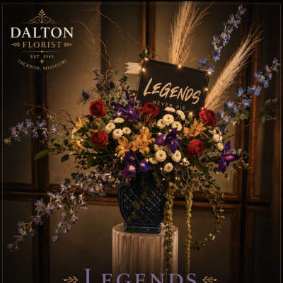 Large floral arrangement with red, purple, yellow, and white flowers in a dark vase