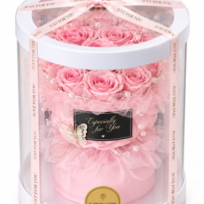 Pink roses arranged in a round gift box with ribbon and pearl accents