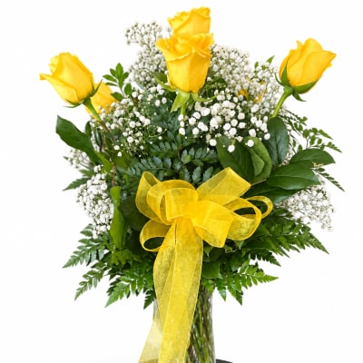 Yellow roses and baby's breath in a glass vase with a yellow ribbon