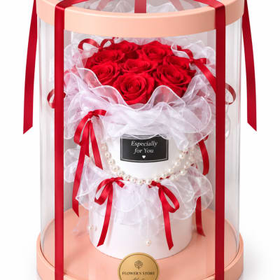 Red roses arranged in a white gift box with ribbons and a clear dome cover.