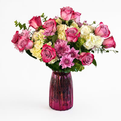 Pink and white mixed flower bouquet in a purple glass vase