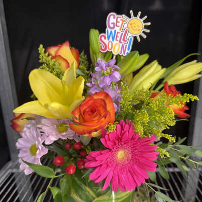 Mixed bouquet with lilies, roses, and a pink gerbera daisy in a glass vase