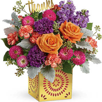 Mixed bouquet with orange roses, purple blooms, and a gold "thanks" pick in a yellow box