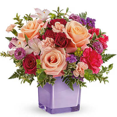 Mixed bouquet of peach, pink, and purple flowers in a purple vase