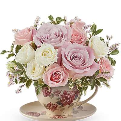 Pink and white roses arranged in a floral teacup with saucer