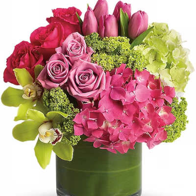 Pink roses, tulips, hydrangea, and orchids in a green glass vase