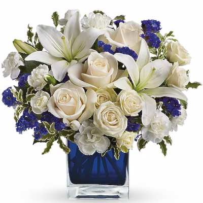 White lilies and roses arranged in a blue glass vase