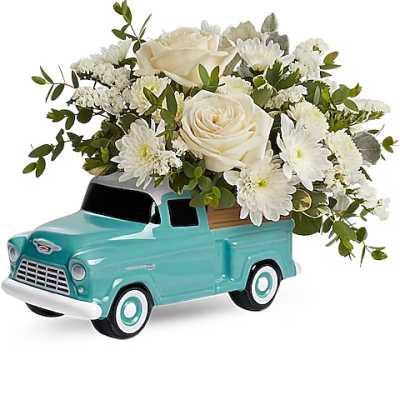 White roses and daisies arranged in a turquoise truck planter