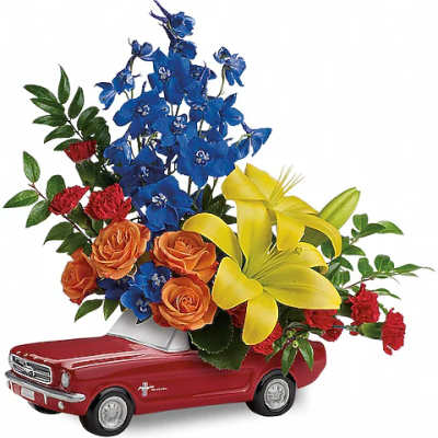 Flower arrangement in a red toy car with blue, yellow, orange, and red blooms