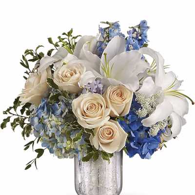 White roses and blue flowers arranged in a glass vase