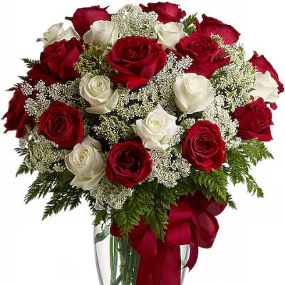 Red and white roses arranged in a clear glass vase with a red ribbon