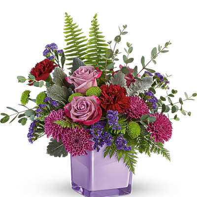 Purple and pink flower arrangement in a lavender glass vase