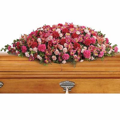 Pink and red floral casket spray on a wooden coffin
