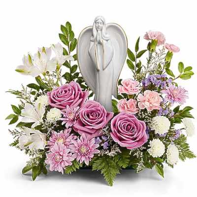 Pink roses and white lilies arranged around a white angel figurine