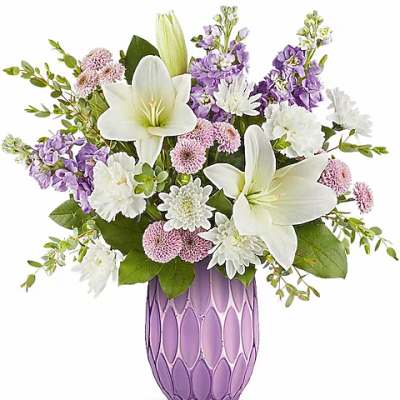 White lilies and purple flowers arranged in a lavender vase