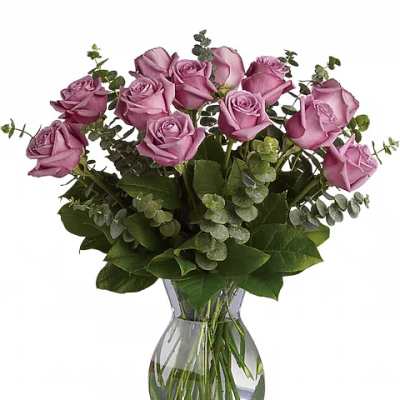 Pink roses arranged in a clear glass vase with greenery