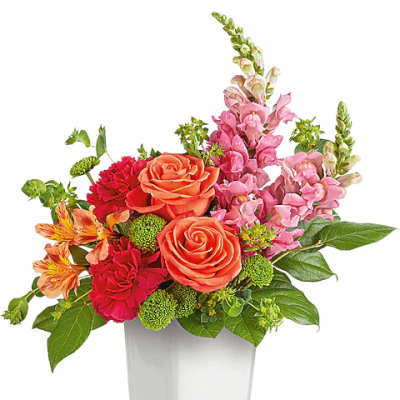 Mixed bouquet of orange roses, pink snapdragons, and red carnations in a clear vase