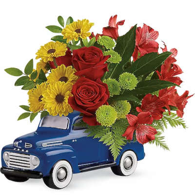 Bouquet of red roses, yellow daisies, and red alstroemeria in a blue truck container