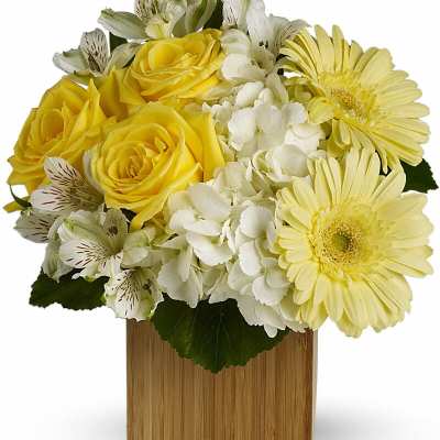 Yellow roses and gerbera daisies in a wooden cube vase