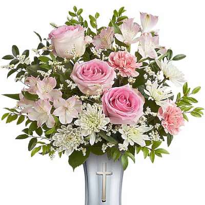 Pink roses and white flowers arranged in a silver vase with a cross