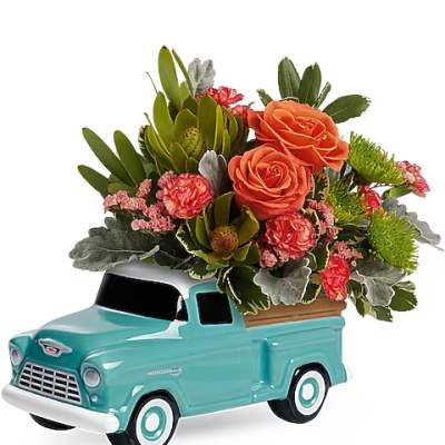 Flower arrangement in a turquoise ceramic truck planter