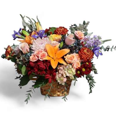 Mixed bouquet in a woven basket with orange lilies, roses, and purple flowers