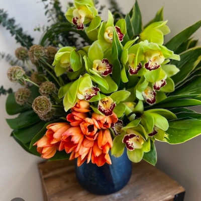 Bouquet of green and orange orchids in a blue vase