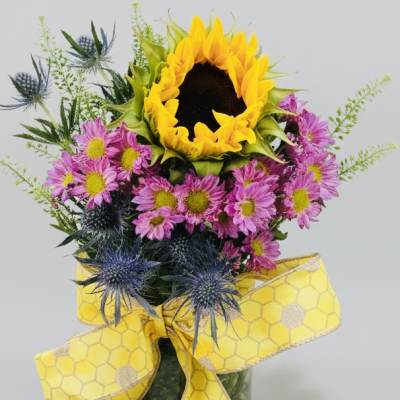 Sunflower bouquet with pink daisies and blue thistle, tied with a yellow ribbon