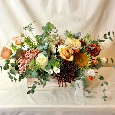 Mixed bouquet in a wooden box with roses, chrysanthemums, and sunflowers