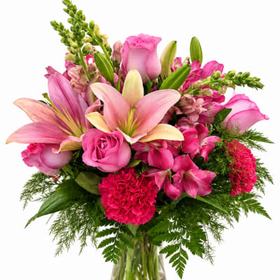 Pink lilies, roses, and carnations in a clear glass vase