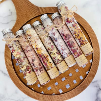Set of floral bath salt tubes tied with twine on a wooden tray
