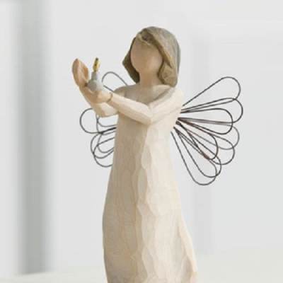 Wooden angel figurine holding a small candle