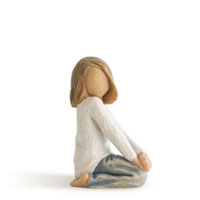 Carved figurine of a seated girl in a white top and blue pants, shown in side profile.