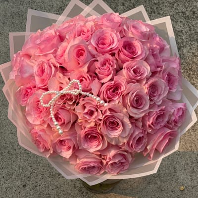 Pink rose bouquet with a pearl bow and translucent wrap