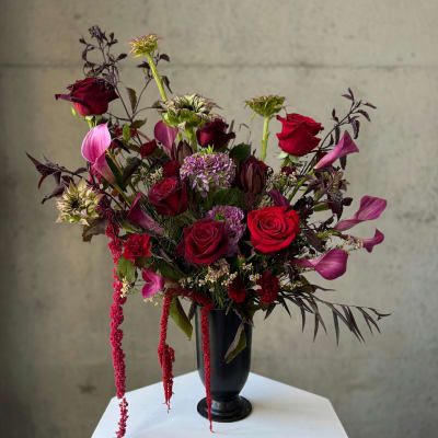Red roses and purple calla lilies in a black vase