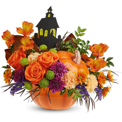 Halloween bouquet in an orange pumpkin container with a haunted house topper