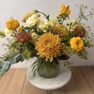 Mixed yellow and cream flowers arranged in a glass vase
