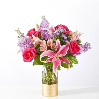 Pink and purple mixed bouquet in a clear vase with a gold base