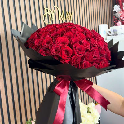 Large bouquet of red roses wrapped in black paper with a red ribbon