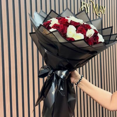 Bouquet of red and white roses wrapped in black paper