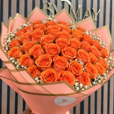 Bouquet of orange roses wrapped in pink paper