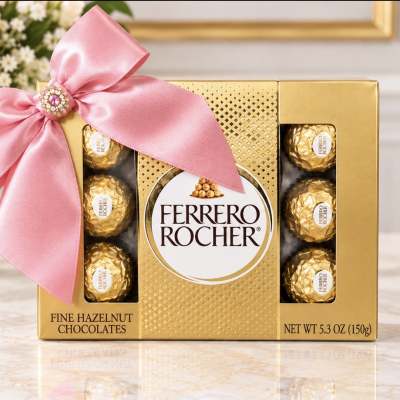 Ferrero Rocher chocolate box with a pink ribbon and flowers in the background