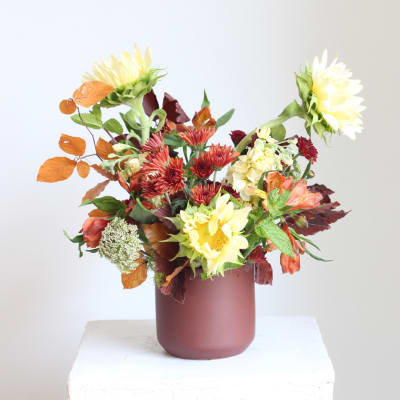 Mixed bouquet of yellow and red flowers in a mauve vase