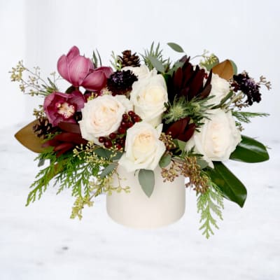 White and pink floral arrangement in a cream vase