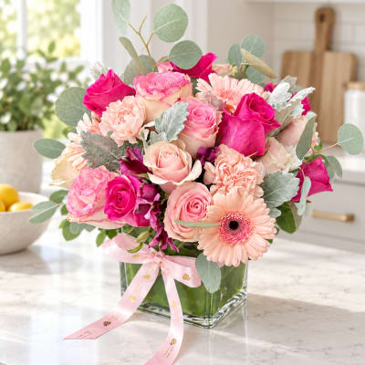 Pink and peach roses with gerbera daisies in a square glass vase